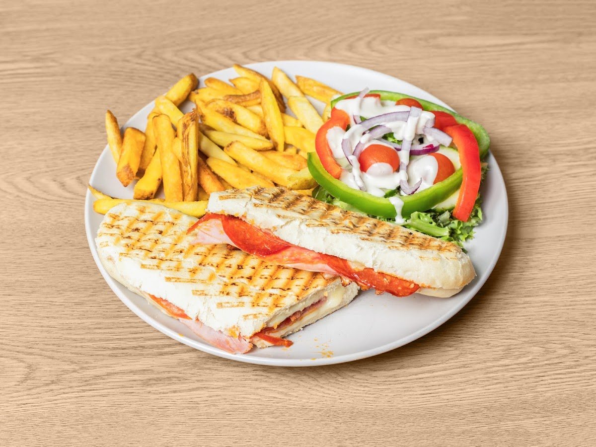 A grill-striped toasted panini with ham, pepperoni and melted cheese, with chips and a fresh salad of peppers, tomato, red onion and dressing.
