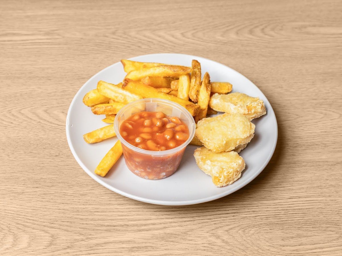 Golden chicken bites with chips and a pot of beans on a white plate.